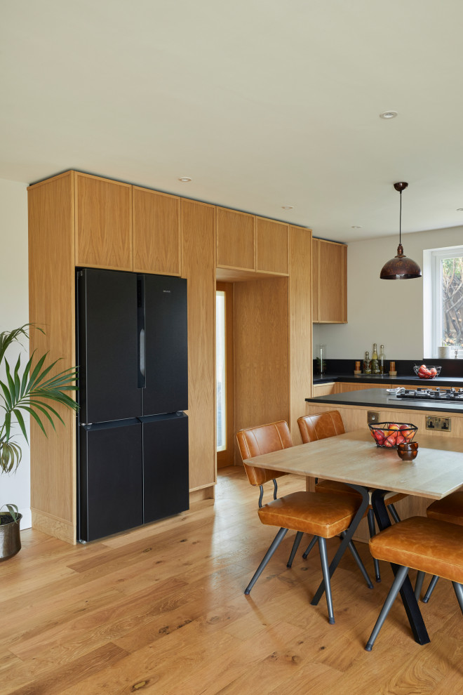 Источник вдохновения для домашнего уюта: большая п-образная кухня в современном стиле с обеденным столом, фасадами в стиле шейкер, островом и черной столешницей