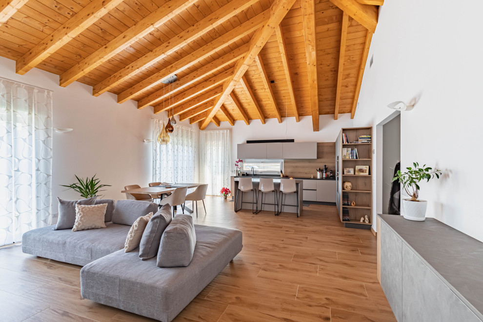 Large modern kitchen/dining combo in Milan with white walls, light hardwood floors, brown floor and exposed beam.