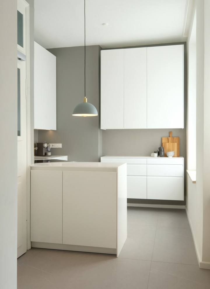 Photo of a small modern l-shaped open plan kitchen in Munich with a built-in sink, beaded cabinets, white cabinets, wood worktops, white splashback, black appliances, no island, grey floors and white worktops.
