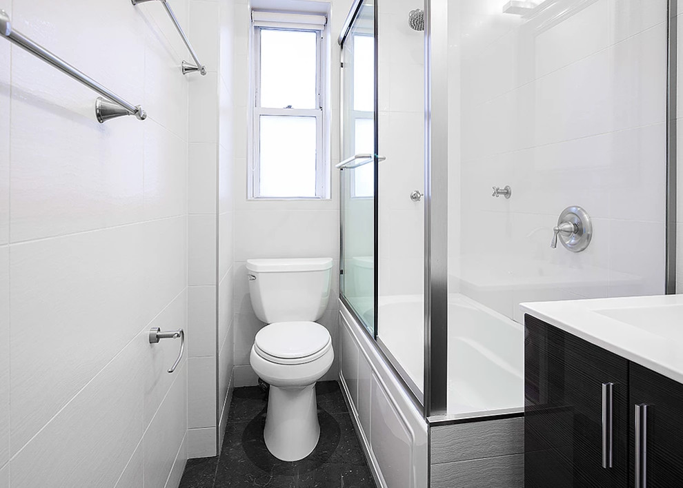Inspiration for a small transitional black floor corner bathtub remodel with flat-panel cabinets, black cabinets, white walls and an integrated sink