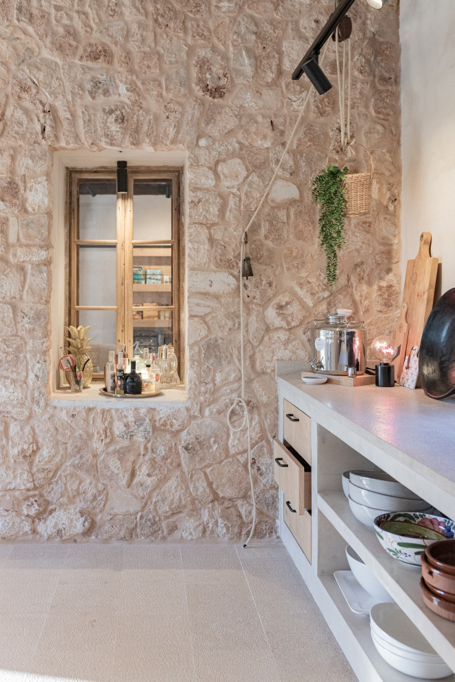 マヨルカ島にあるラグジュアリーな広い地中海スタイルのおしゃれなキッチン (中間色木目調キャビネット、トラバーチンの床、ベージュの床、ベージュのキッチンカウンター、表し梁) の写真