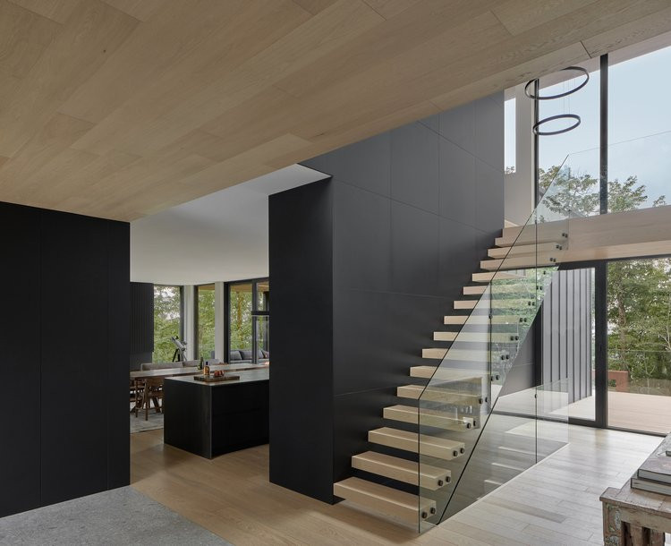 Aménagement d'un très grand escalier sans contremarche moderne avec des marches en bois, un garde-corps en verre et du lambris.