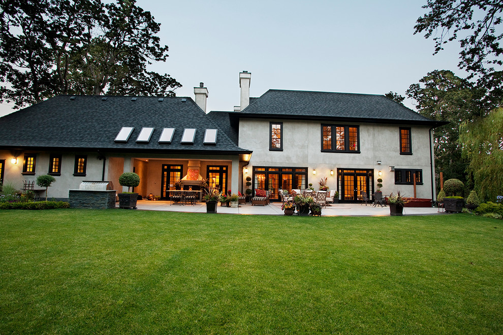 Photo of a large traditional two-storey stucco beige house exterior in Vancouver with a shingle roof.