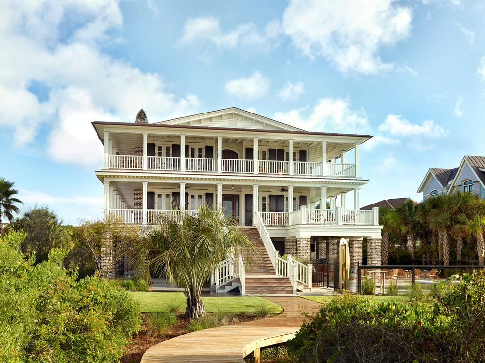 Photo of a large beach style three-storey brick exterior in Charleston with a gable roof.