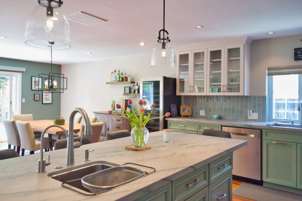 Photo of a large eclectic l-shaped open plan kitchen in San Francisco with an undermount sink, recessed-panel cabinets, green cabinets, granite benchtops, green splashback, ceramic splashback, stainless steel appliances, dark hardwood floors, with island, brown floor and multi-coloured benchtop.