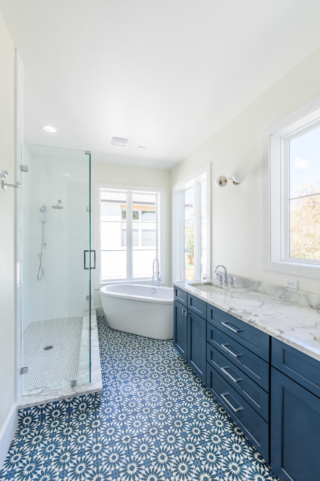 Large country master bathroom in Orlando with shaker cabinets, blue cabinets, a freestanding tub, white tile, subway tile, white walls, mosaic tile floors, an undermount sink, marble benchtops, multi-coloured floor, a hinged shower door and multi-coloured benchtops.