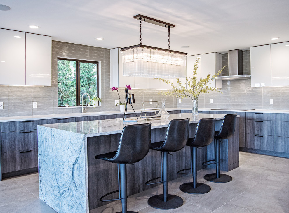 This is an example of a large contemporary l-shaped eat-in kitchen in Seattle with flat-panel cabinets, white cabinets, grey splashback, with island, grey floor, white benchtop and glass tile splashback.