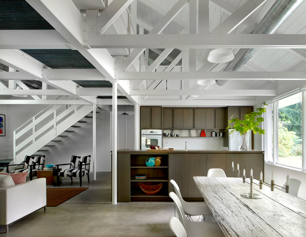 Mid-sized industrial galley open plan kitchen in Chicago with flat-panel cabinets, dark wood cabinets, quartz benchtops, white splashback, white appliances, concrete floors and with island.