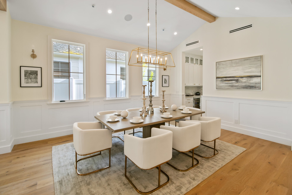 This is an example of a transitional separate dining room in Los Angeles with white walls, medium hardwood floors, no fireplace and brown floor.