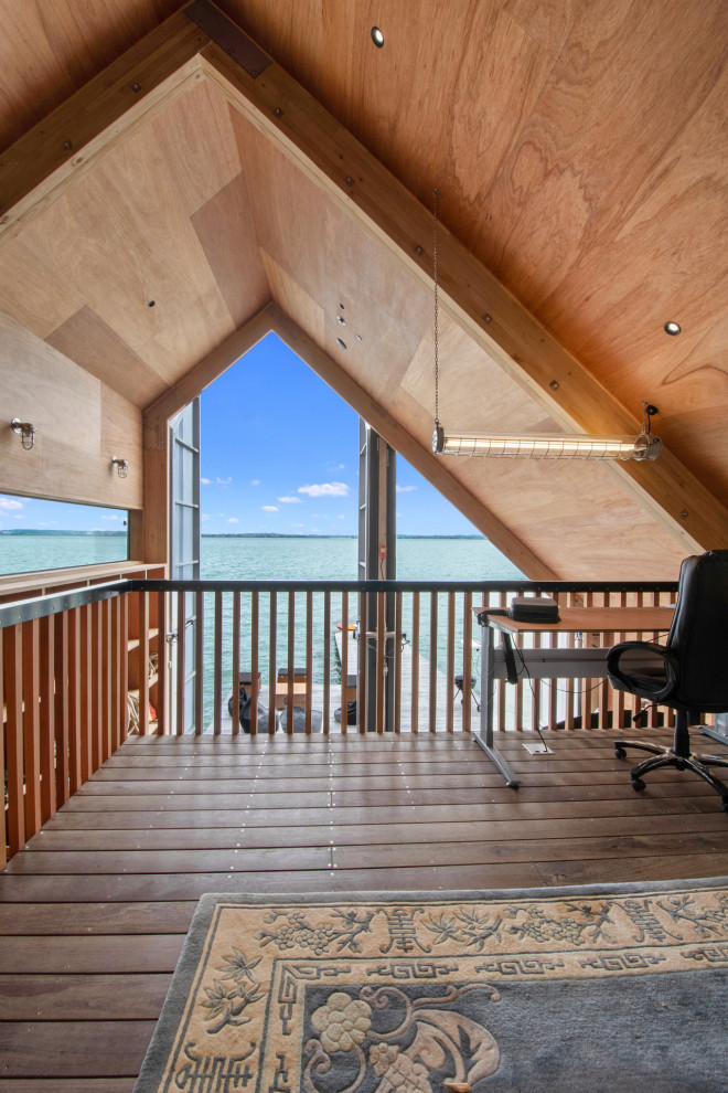 Photo of a small beach style home studio in Auckland with brown walls, a freestanding desk, vaulted, wood walls, light hardwood floors and brown floor.