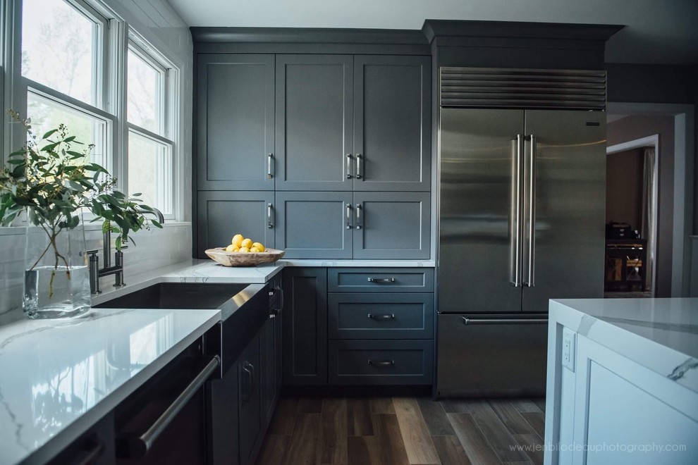 Inspiration for an expansive modern l-shaped eat-in kitchen in Boston with a farmhouse sink, shaker cabinets, white cabinets, quartz benchtops, white splashback, ceramic splashback, stainless steel appliances, light hardwood floors and with island.