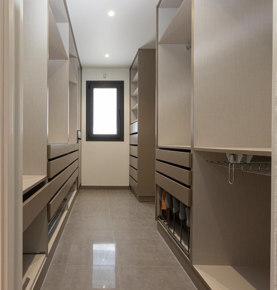 Foto de armario vestidor unisex minimalista grande con armarios abiertos, puertas de armario beige, suelo de baldosas de porcelana y suelo gris