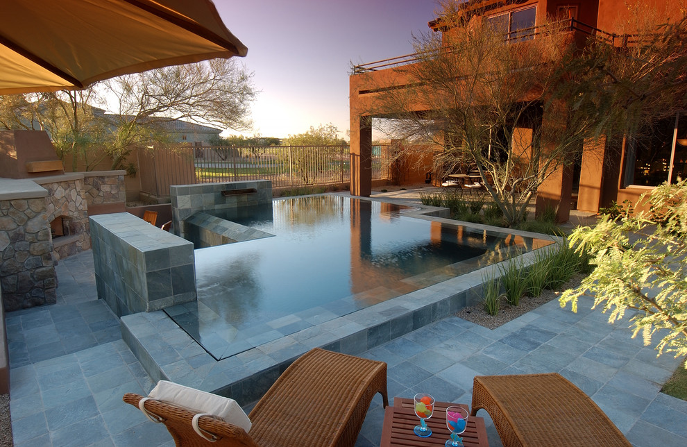 Design ideas for a large modern backyard rectangular infinity pool in Phoenix with a water feature and stamped concrete.