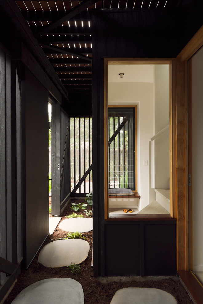 Foto di una porta d'ingresso moderna di medie dimensioni con pareti nere, pavimento in cemento, una porta scorrevole, una porta nera, travi a vista e pareti in legno