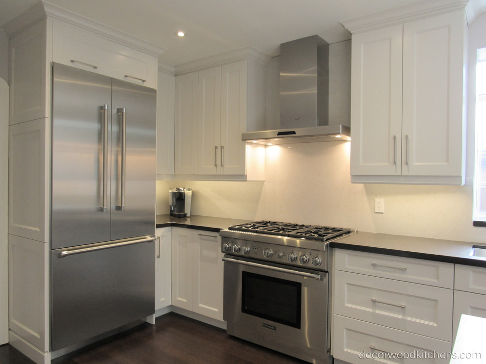 Enclosed kitchen - large transitional l-shaped dark wood floor enclosed kitchen idea in Toronto with an undermount sink, shaker cabinets, white cabinets, quartz countertops, white backsplash, stone slab backsplash, stainless steel appliances and an island