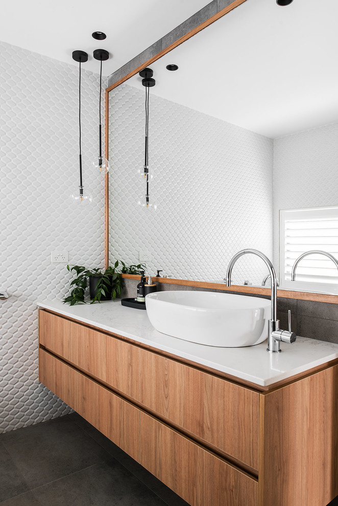 This is an example of a contemporary bathroom in Hobart with flat-panel cabinets, medium wood cabinets, white walls, a vessel sink, grey floor and white benchtops.