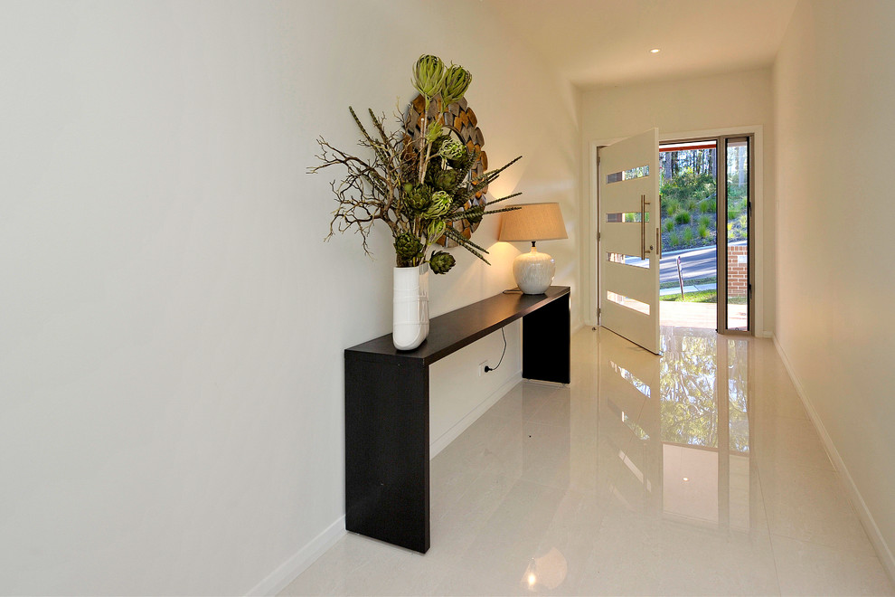 This is an example of a mid-sized contemporary foyer in Newcastle - Maitland with white walls, porcelain floors, a pivot front door and a white front door.
