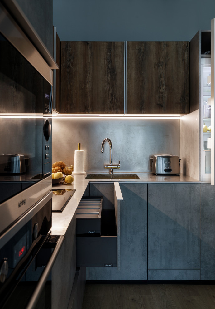 This is an example of a small contemporary l-shaped eat-in kitchen in Moscow with a single-bowl sink, grey cabinets, stainless steel benchtops, grey splashback, panelled appliances, no island and grey benchtop.