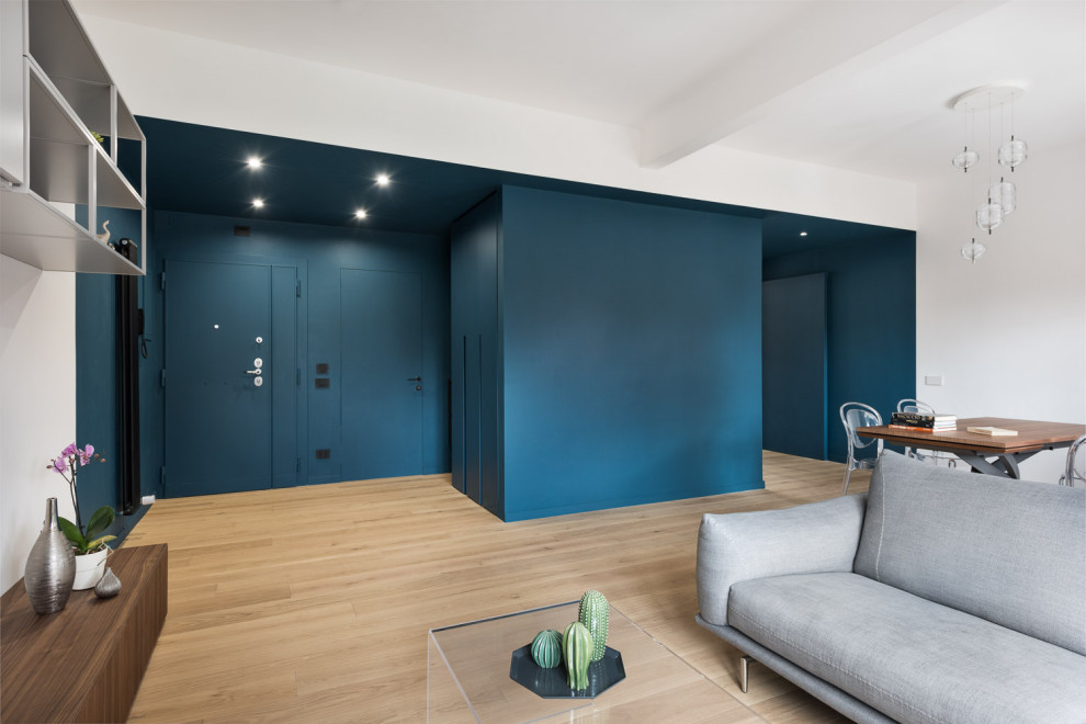 Cette photo montre une entrée tendance avec un mur bleu, parquet clair et une porte bleue.