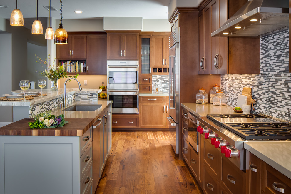 Photo of a large transitional l-shaped eat-in kitchen in San Diego with an undermount sink, recessed-panel cabinets, medium wood cabinets, quartz benchtops, multi-coloured splashback, matchstick tile splashback, stainless steel appliances, medium hardwood floors and with island.