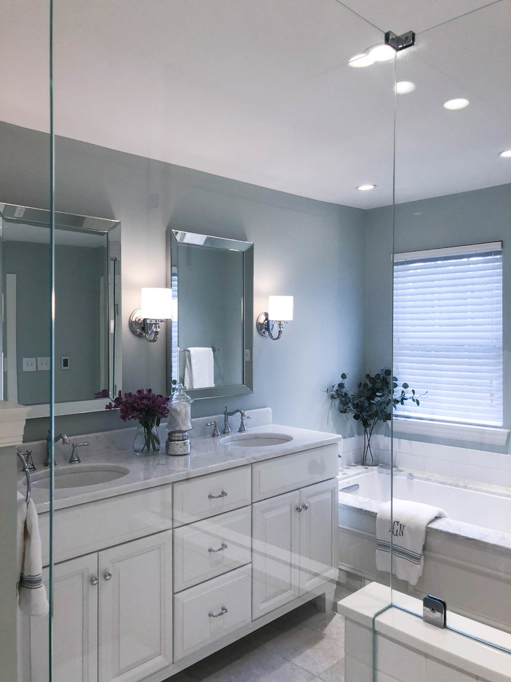 This is an example of a small transitional bathroom in Philadelphia with shaker cabinets, white cabinets, a corner tub, a corner shower, a one-piece toilet, white tile, grey walls, an integrated sink, marble benchtops, white floor, a hinged shower door, white benchtops, a double vanity and a freestanding vanity.