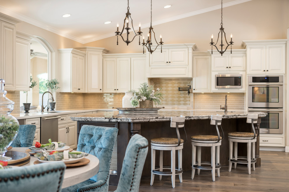Inspiration for a large transitional l-shaped medium tone wood floor and brown floor eat-in kitchen remodel in Phoenix with an undermount sink, raised-panel cabinets, beige cabinets, quartz countertops, beige backsplash, glass tile backsplash, stainless steel appliances and an island
