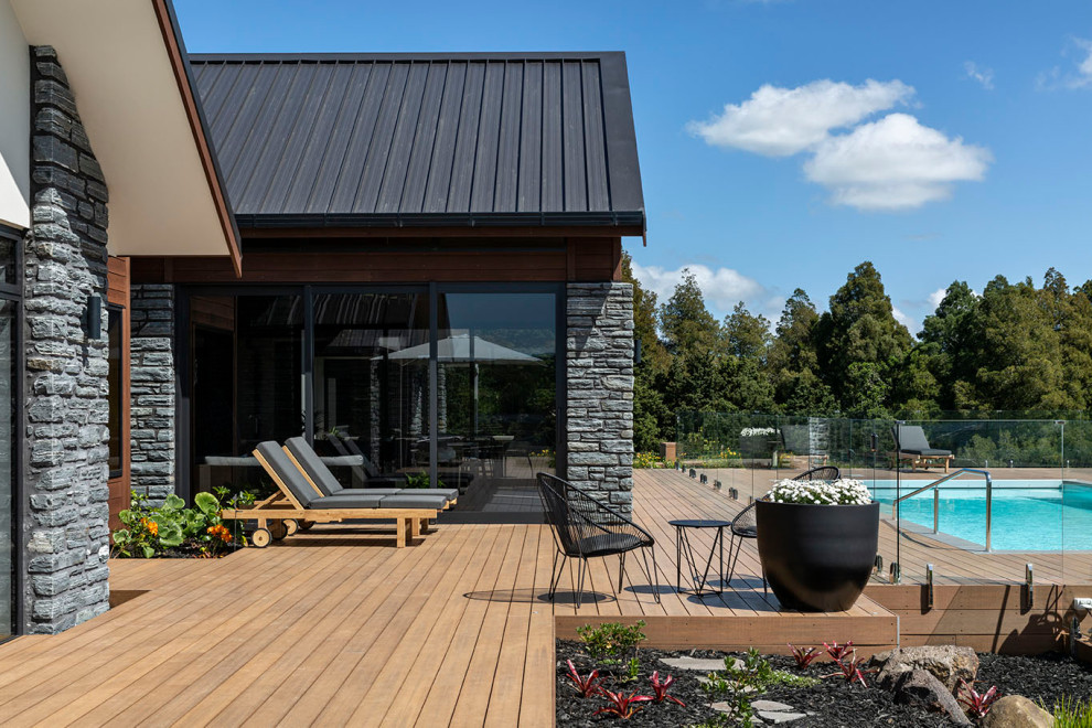 Cette photo montre une grande piscine arrière tendance rectangle avec une terrasse en bois.