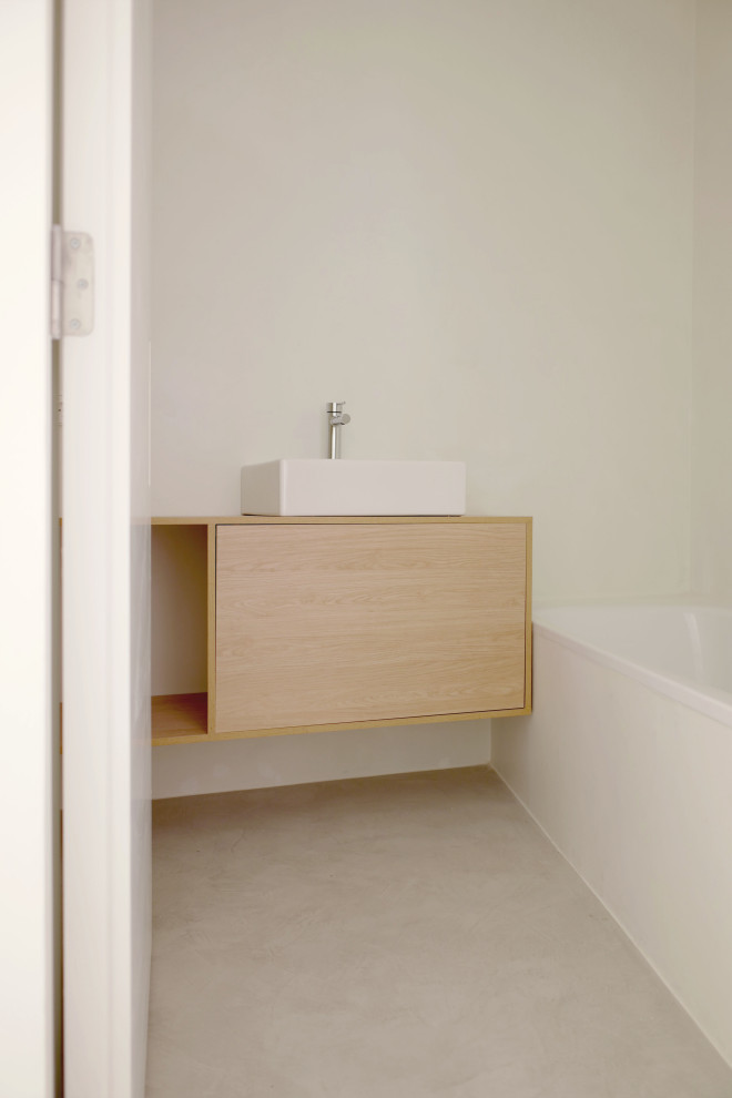Idéer för ett litet brun badrum med dusch, med släta luckor, vita skåp, ett platsbyggt badkar, grå kakel, cementkakel, vita väggar, betonggolv, ett fristående handfat, träbänkskiva och grått golv