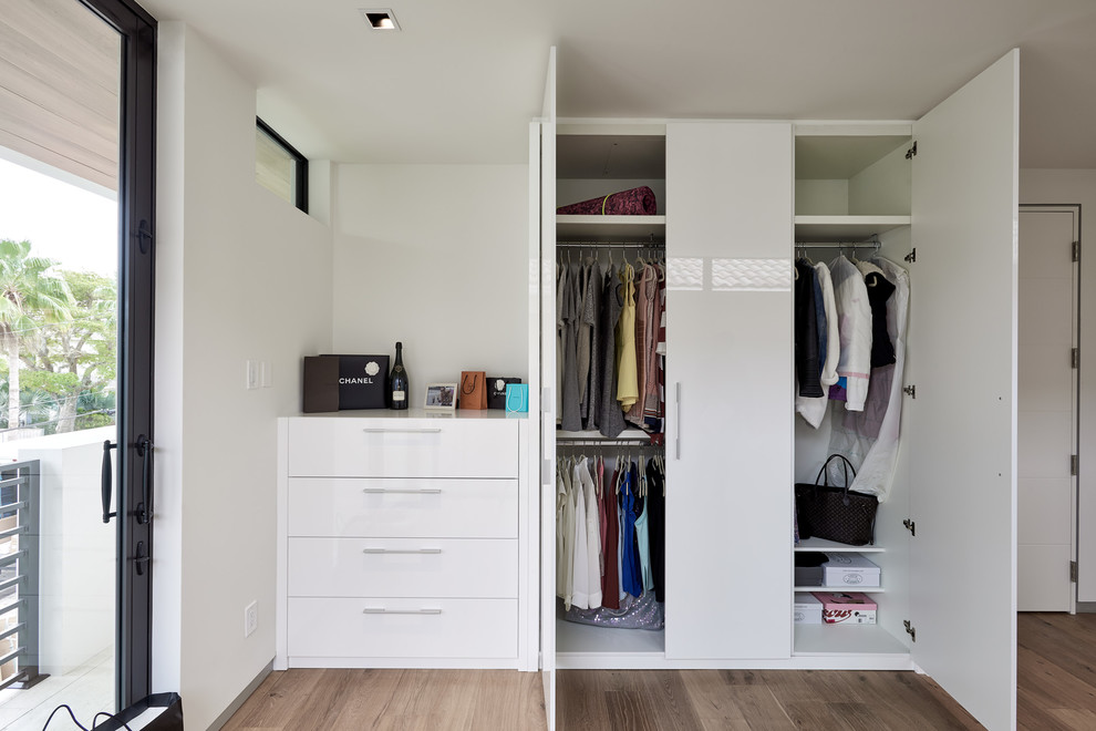 Example of a trendy reach-in closet design in Miami with flat-panel cabinets and white cabinets