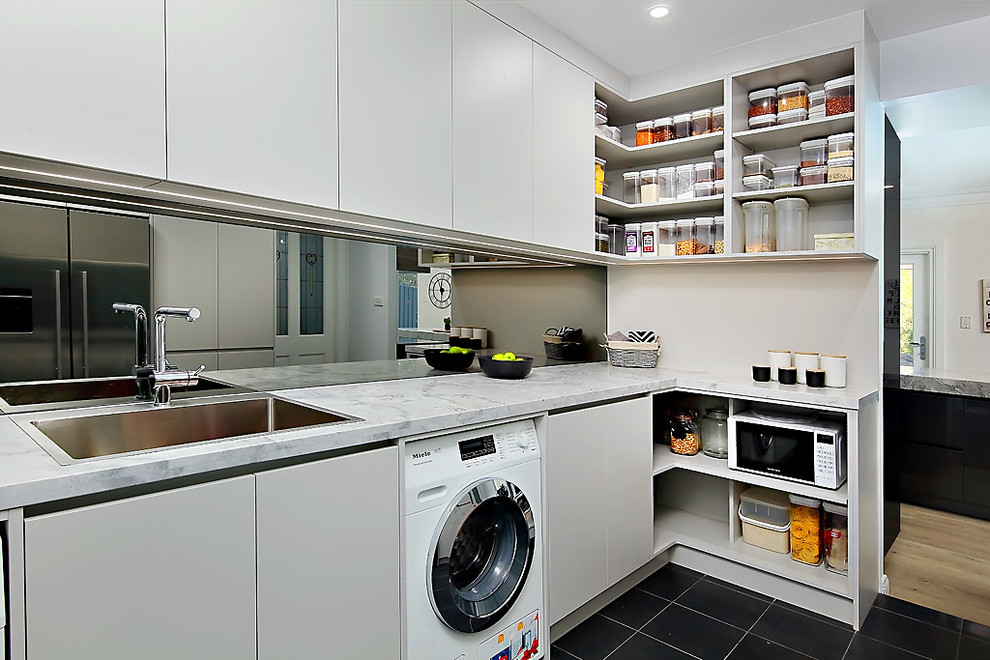 Photo of a large contemporary galley open plan kitchen in Sydney with a drop-in sink, marble benchtops, stone slab splashback, black appliances and with island.