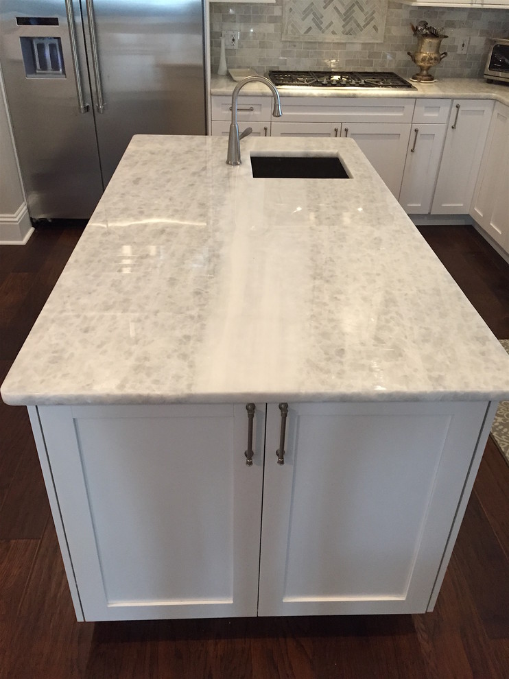 Example of a mid-sized transitional u-shaped dark wood floor eat-in kitchen design in Tampa with an undermount sink, shaker cabinets, white cabinets, marble countertops, stone tile backsplash, stainless steel appliances and an island