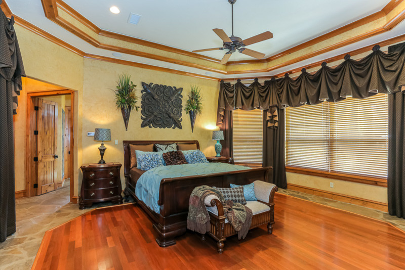 Inspiration for a large mediterranean master bedroom in Houston with yellow walls and medium hardwood floors.