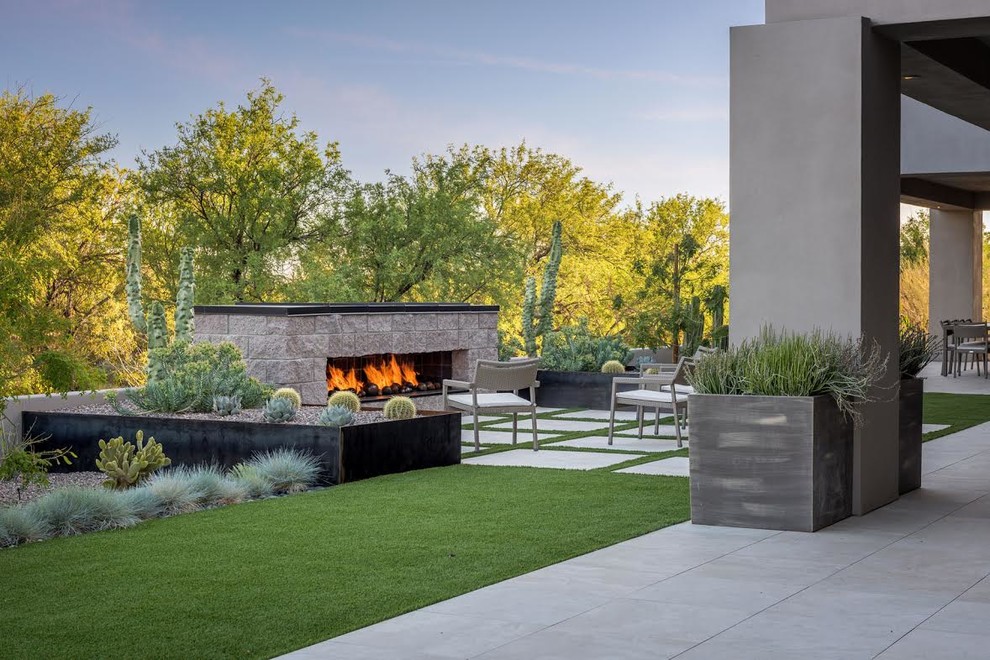 This is an example of a large modern backyard patio in Phoenix with a fire feature, concrete slab and a roof extension.