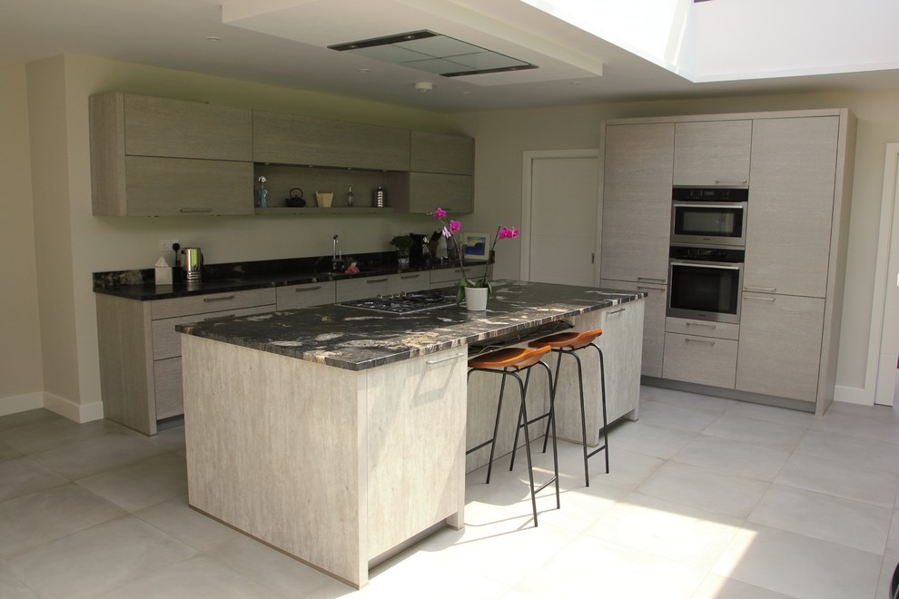 This is an example of a mid-sized contemporary l-shaped eat-in kitchen in Surrey with flat-panel cabinets, light wood cabinets, granite benchtops, stainless steel appliances and with island.