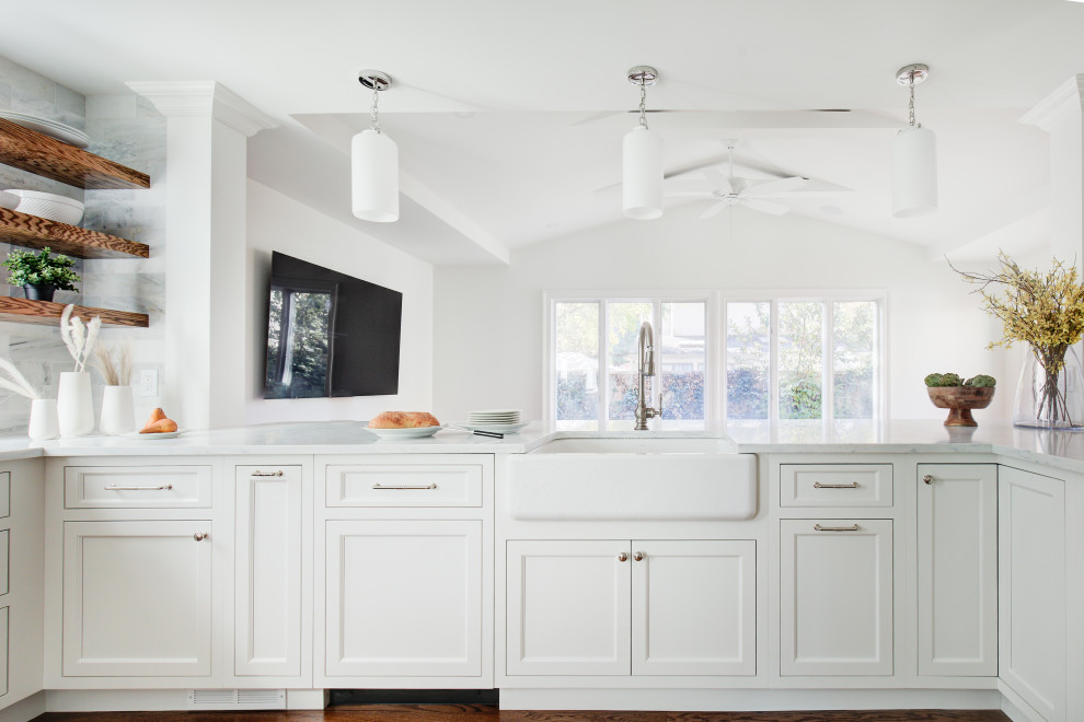Example of a mid-sized transitional u-shaped medium tone wood floor and brown floor open concept kitchen design with a farmhouse sink, recessed-panel cabinets, white cabinets, quartz countertops, multicolored backsplash, marble backsplash, stainless steel appliances, a peninsula and white countertops