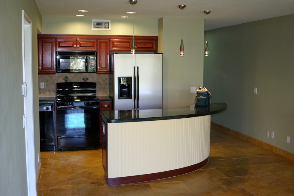 Mid-sized beach style l-shaped separate kitchen in Los Angeles with an undermount sink, raised-panel cabinets, red cabinets, granite benchtops, beige splashback, ceramic splashback, black appliances, ceramic floors and with island.