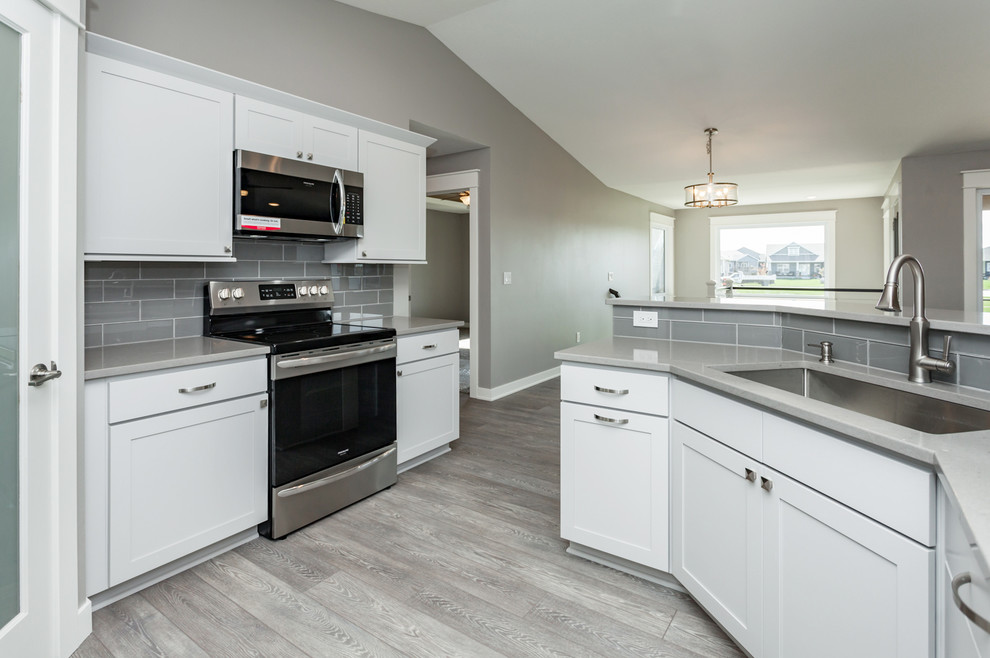 Kitchen - mid-sized transitional u-shaped medium tone wood floor and gray floor kitchen idea with an undermount sink, shaker cabinets, white cabinets, quartz countertops, gray backsplash, ceramic backsplash, stainless steel appliances, no island and gray countertops