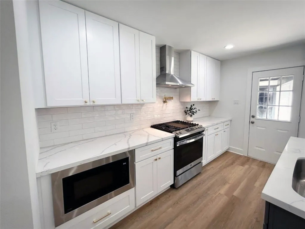 Large light wood floor and beige floor eat-in kitchen photo with marble countertops, marble backsplash and stainless steel appliances