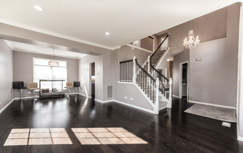 This is an example of a large transitional open concept living room in Chicago with grey walls, dark hardwood floors, no fireplace and grey floor.