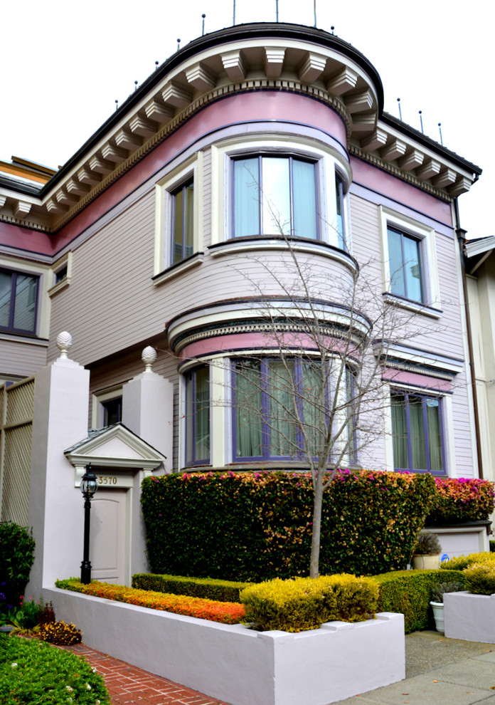 Inspiration for a mid-sized traditional two-storey pink apartment exterior in San Francisco with wood siding, a flat roof and a shingle roof.