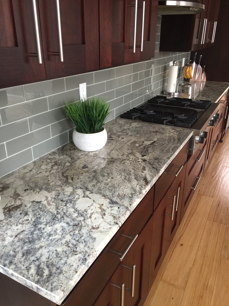 Inspiration for a transitional kitchen remodel with shaker cabinets, dark wood cabinets, granite countertops, gray backsplash, glass tile backsplash and stainless steel appliances