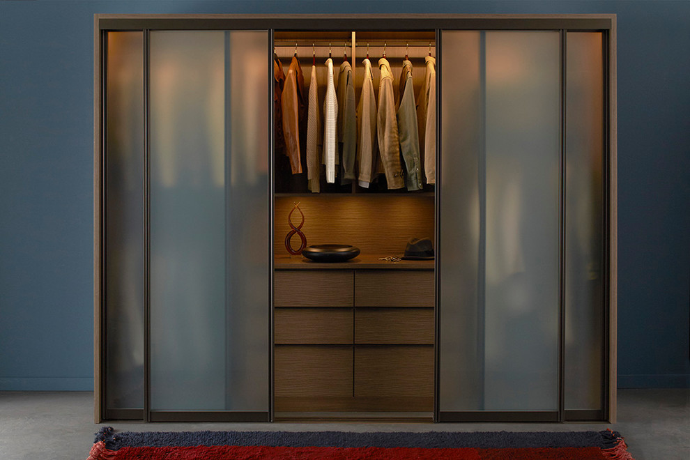 Mid-sized midcentury gender-neutral built-in wardrobe in Nashville with flat-panel cabinets, dark wood cabinets and concrete floors.