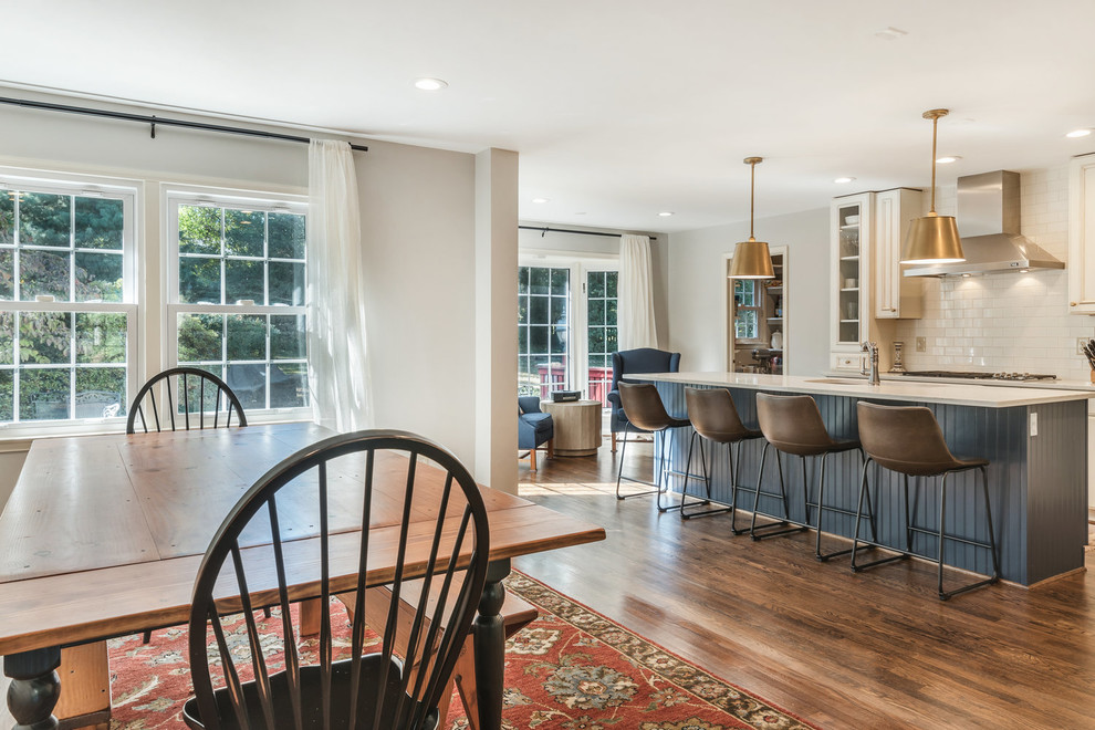 Transitional medium tone wood floor and brown floor eat-in kitchen photo in DC Metro with an undermount sink, recessed-panel cabinets, white cabinets, granite countertops, white backsplash, subway tile backsplash, stainless steel appliances, an island and white countertops