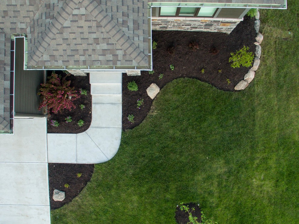 This is an example of a small modern front yard partial sun xeriscape for summer in Omaha with a garden path and mulch.