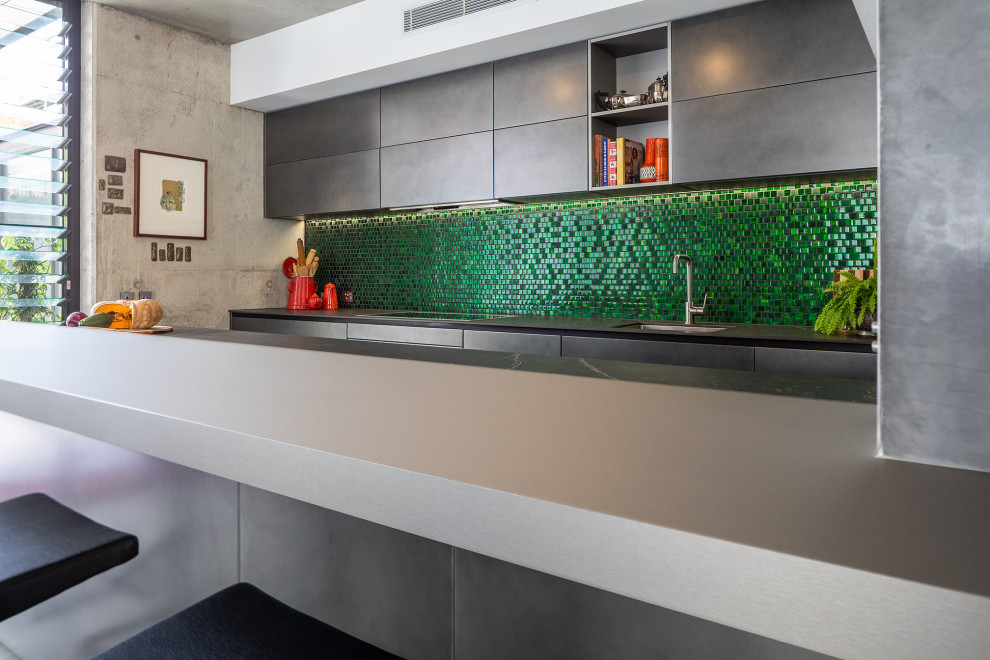 Design ideas for a large eclectic open plan kitchen in Perth with an undermount sink, green splashback, glass tile splashback, panelled appliances, concrete floors, with island and grey benchtop.