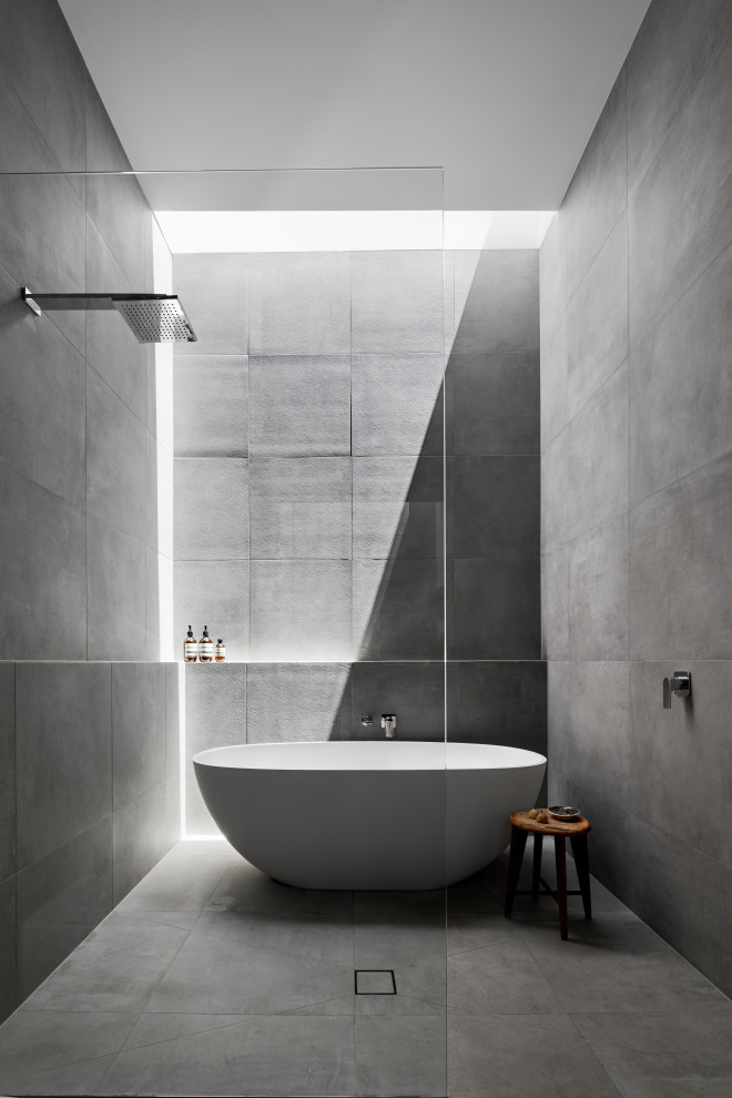 This is an example of a large contemporary master wet room bathroom in Melbourne with a freestanding tub, gray tile, porcelain tile, porcelain floors, grey floor, a wall-mount toilet, grey walls, a drop-in sink, engineered quartz benchtops, an open shower and white benchtops.