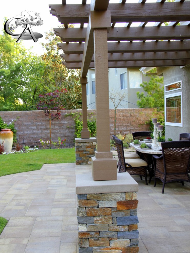 This is an example of a mid-sized transitional backyard patio in Orange County with an outdoor kitchen, concrete pavers and a pergola.