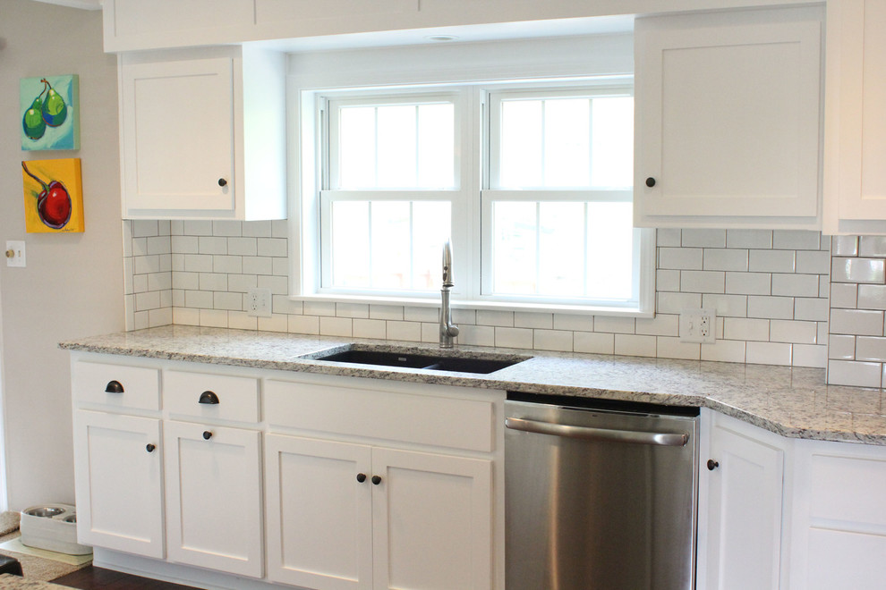 Photo of a mid-sized traditional u-shaped eat-in kitchen in Kansas City with shaker cabinets, white cabinets, granite benchtops, white splashback, subway tile splashback, stainless steel appliances, medium hardwood floors, a peninsula and a double-bowl sink.