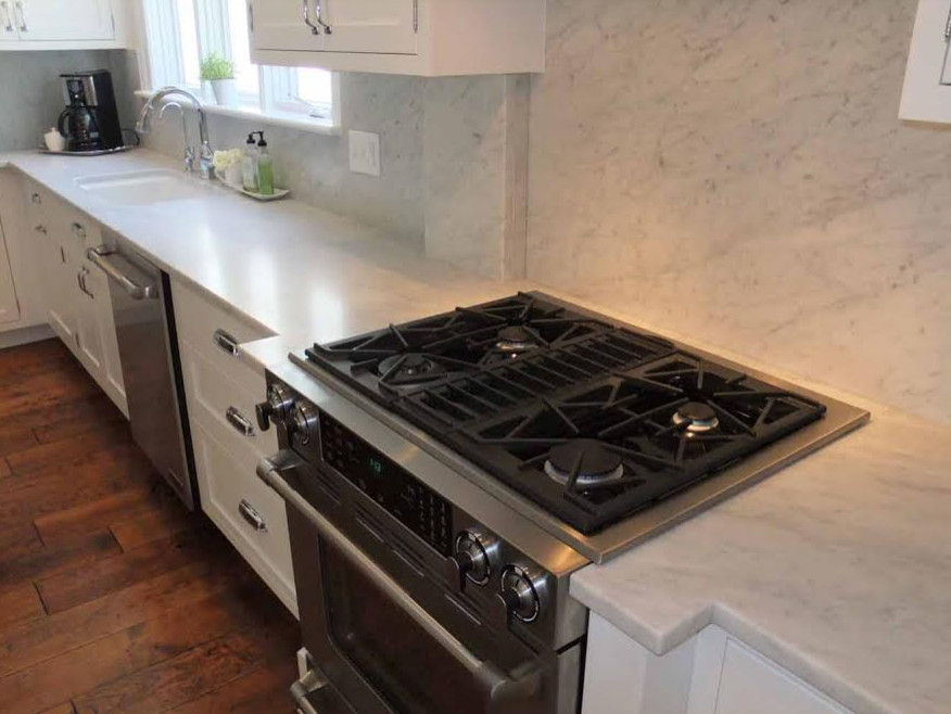 Enclosed kitchen - large transitional l-shaped medium tone wood floor enclosed kitchen idea in Indianapolis with an undermount sink, shaker cabinets, white cabinets, marble countertops, gray backsplash, stone slab backsplash, stainless steel appliances and no island