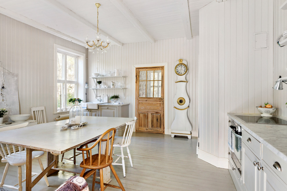 This is an example of a mid-sized traditional l-shaped eat-in kitchen in Stockholm with a farmhouse sink, raised-panel cabinets, grey cabinets, stainless steel appliances, painted wood floors, no island and marble benchtops.